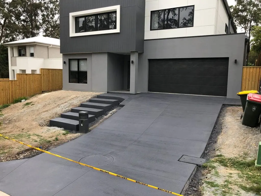 Charcoal concrete driveway with floating block steps at a modern home