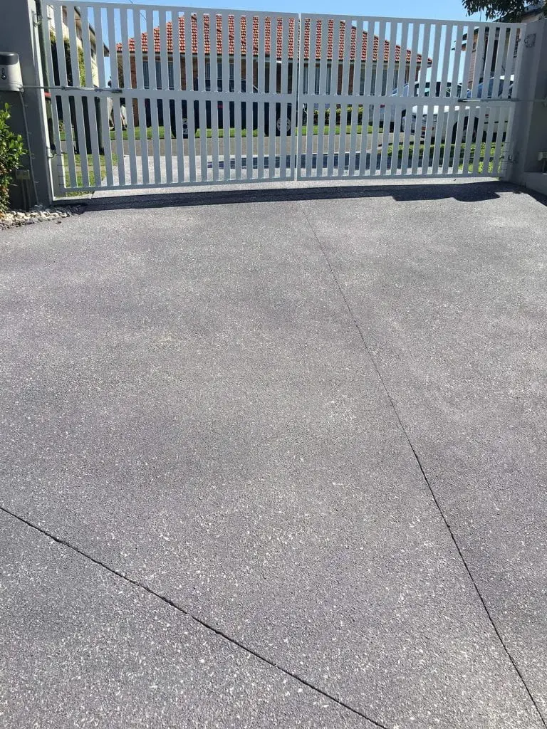 Driveway resurfaced in a charcoal fleck finish inside a white gate
