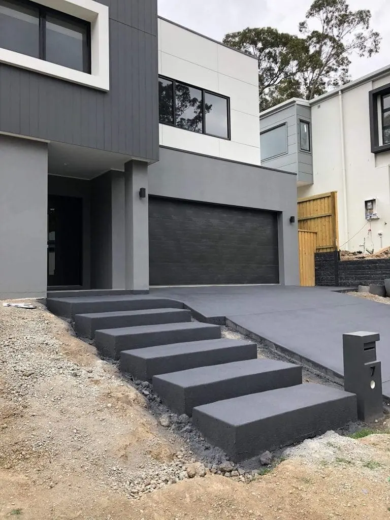 Charcoal floating concrete entry steps beside a matching driveway