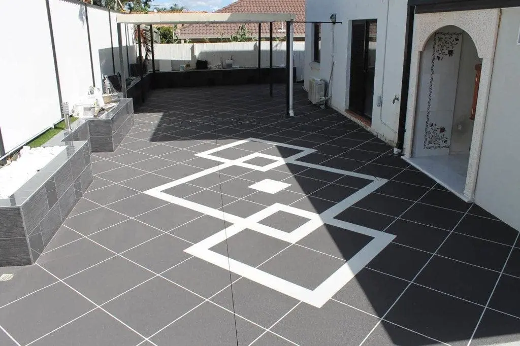 Resurfaced charcoal tile-pattern patio with a white geometric feature border