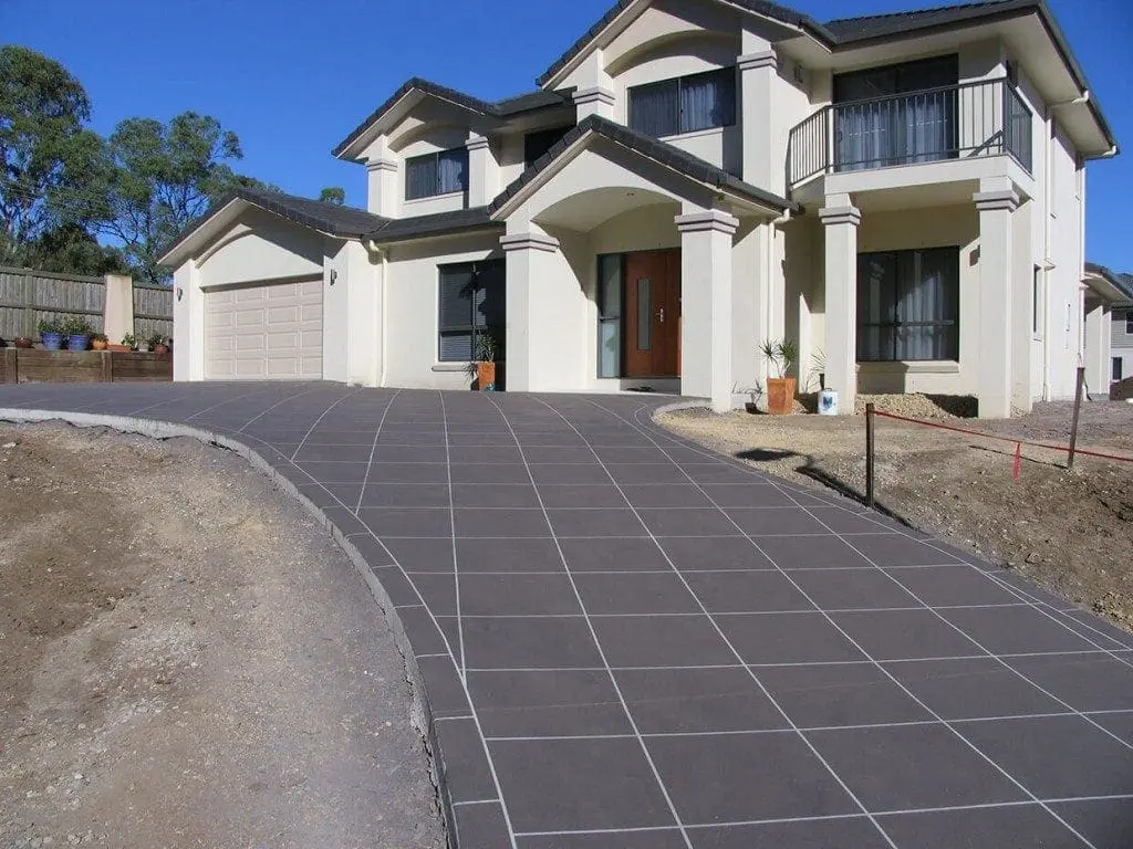 Curved driveway resurfaced in charcoal square tiles at a two-storey home