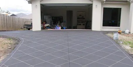 Charcoal tile-stencilled concrete driveway outside a double garage