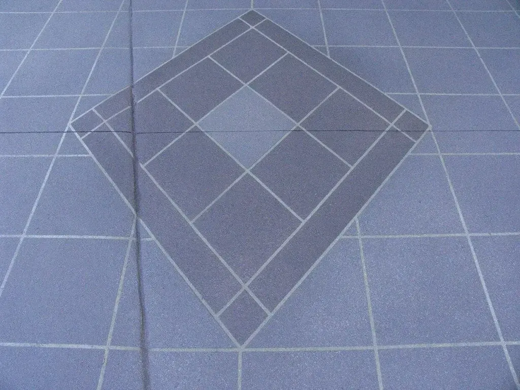 Close-up of a layered diamond feature inlay in a grey tile-pattern driveway
