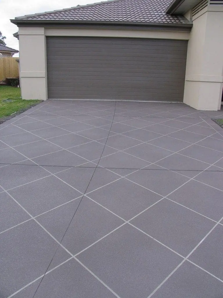 Grey diamond-tile resurfaced driveway in front of a charcoal garage door