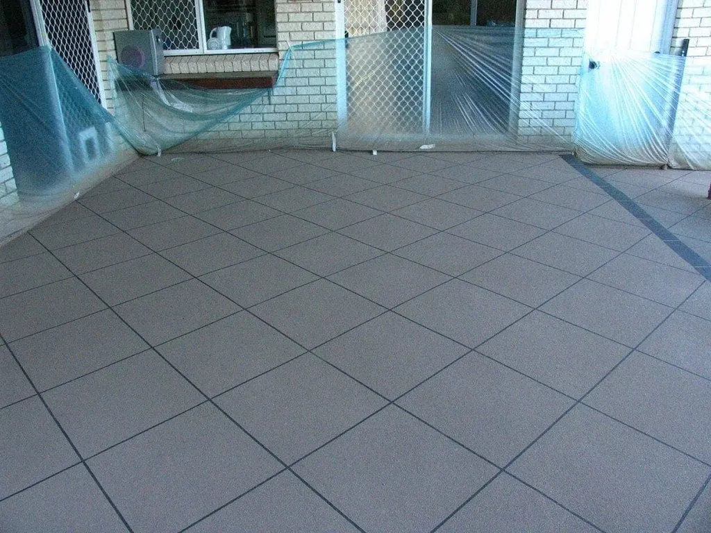Patio resurfaced in grey diamond tiles with the masking still in place