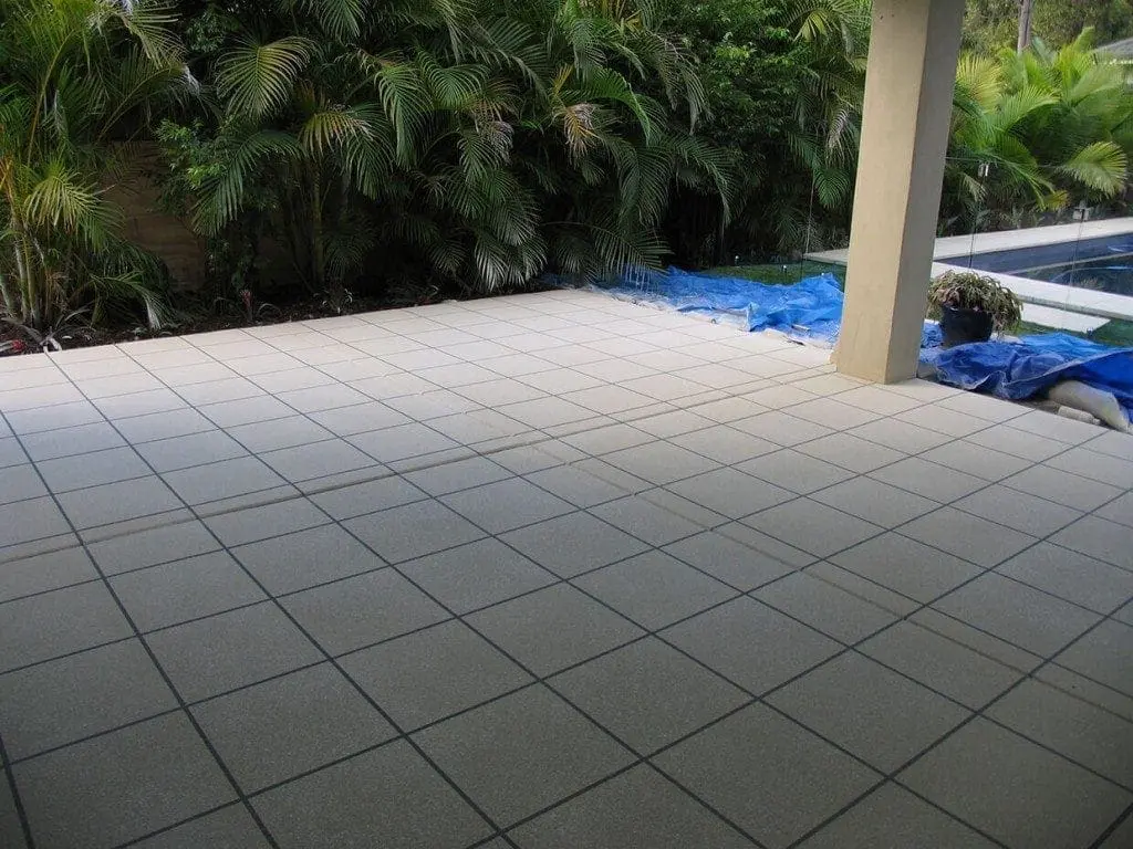 Covered patio beside a pool resurfaced in light grey square tiles