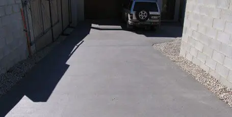 Plain grey concrete side driveway between block walls