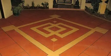 Terracotta coloured concrete patio with a sandstone geometric border