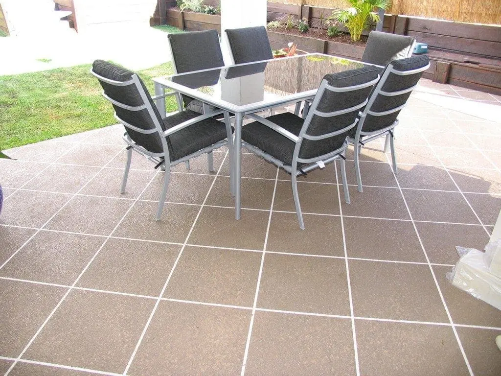 Backyard patio resurfaced in a mocha tile pattern with white grout lines