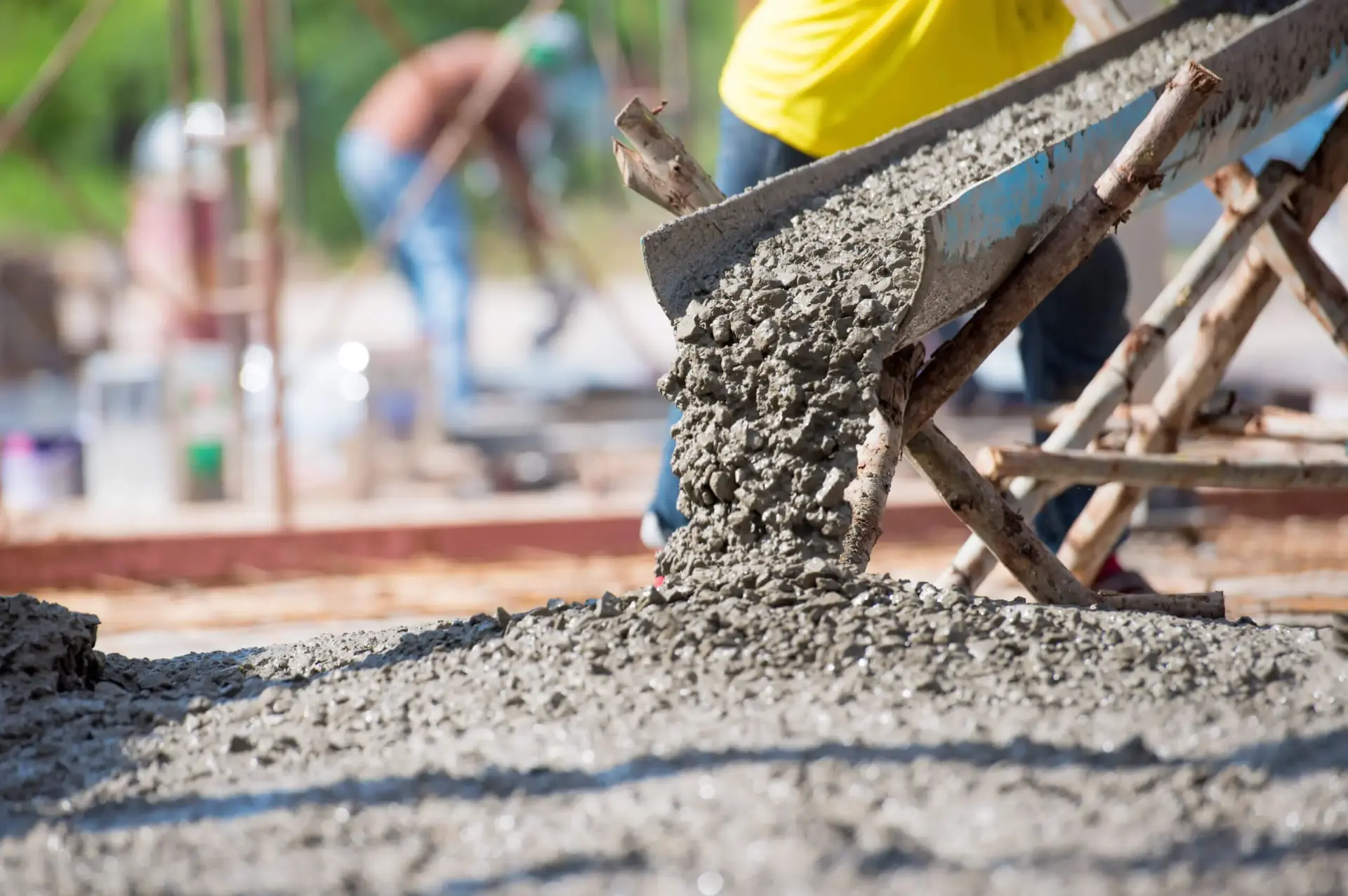 Fresh concrete pouring from a truck chute onto a reinforced slab